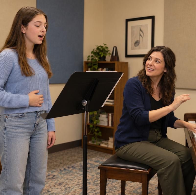 Voice student singing at a music stand while her teacher accompanies on piano at New Hudson Music Academy