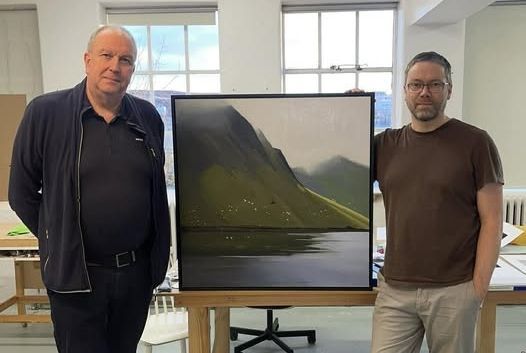 Tveir menn standa við stóran skjá sem sýnir fjallalandslag í björtu herbergi