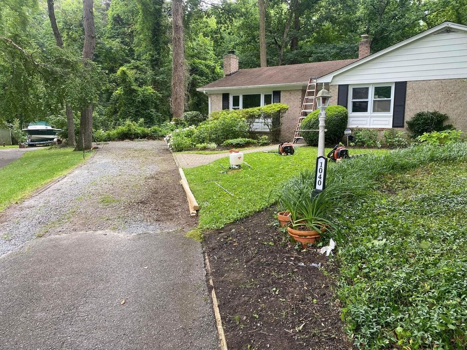 Suburban house with a gravel driveway, front lawn, and wooded yard