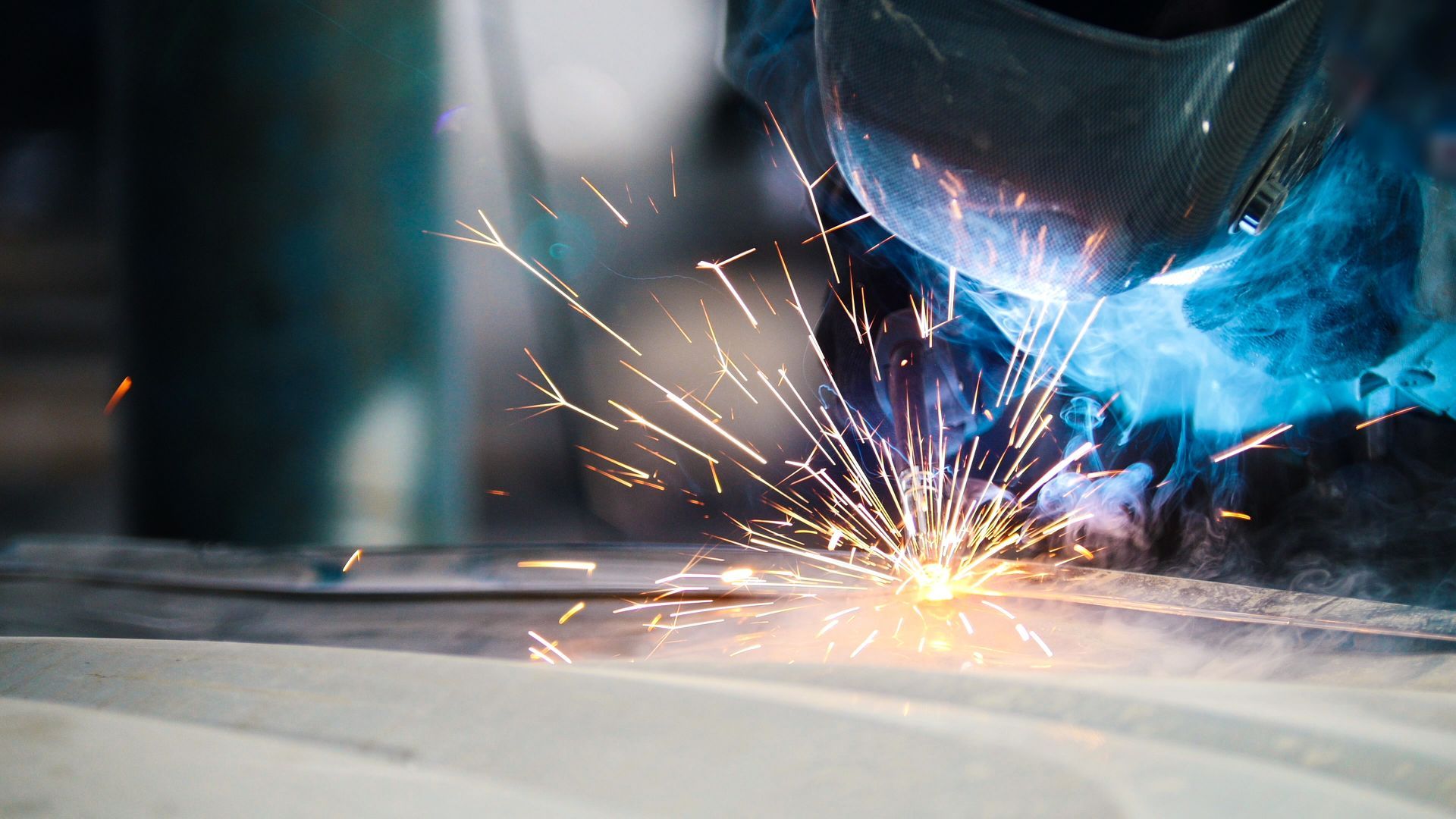 Close-up of welding sparks and smoke as a metal joint is welded on a flat steel surface. Close-up of welding sparks and smoke as a metal joint is welded on a flat steel surface.