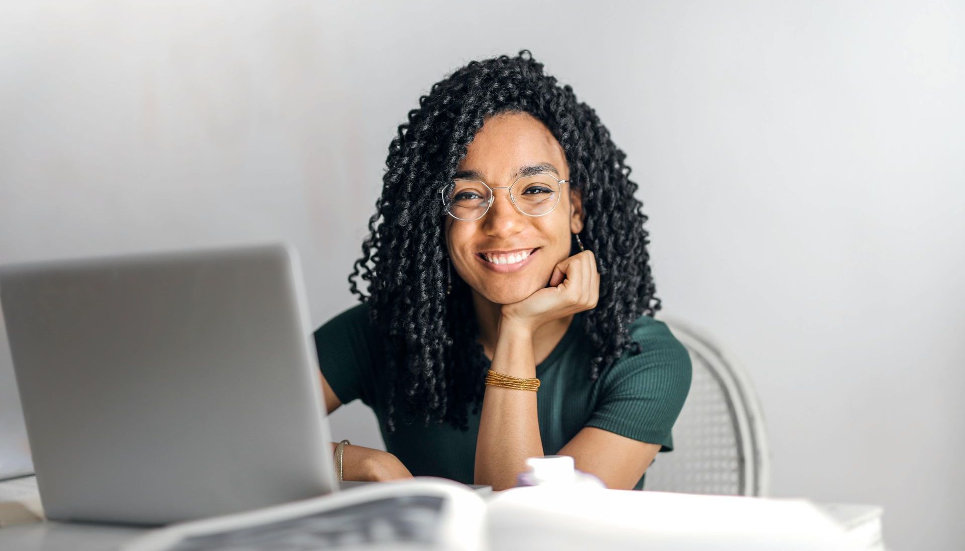 A woman is sitting at a desk in front of a laptop computer.