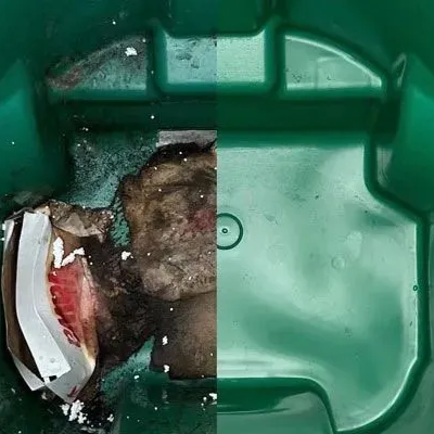A green trash can with a piece of paper in it.