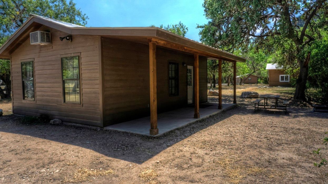A small house with a porch and a picnic table in front of it.