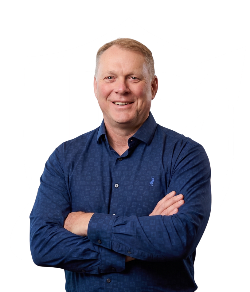 Smiling man in a blue shirt with arms crossed against a white background