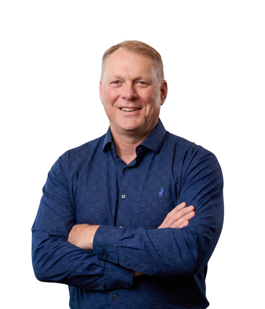 Smiling man in a blue shirt with arms crossed against a white background