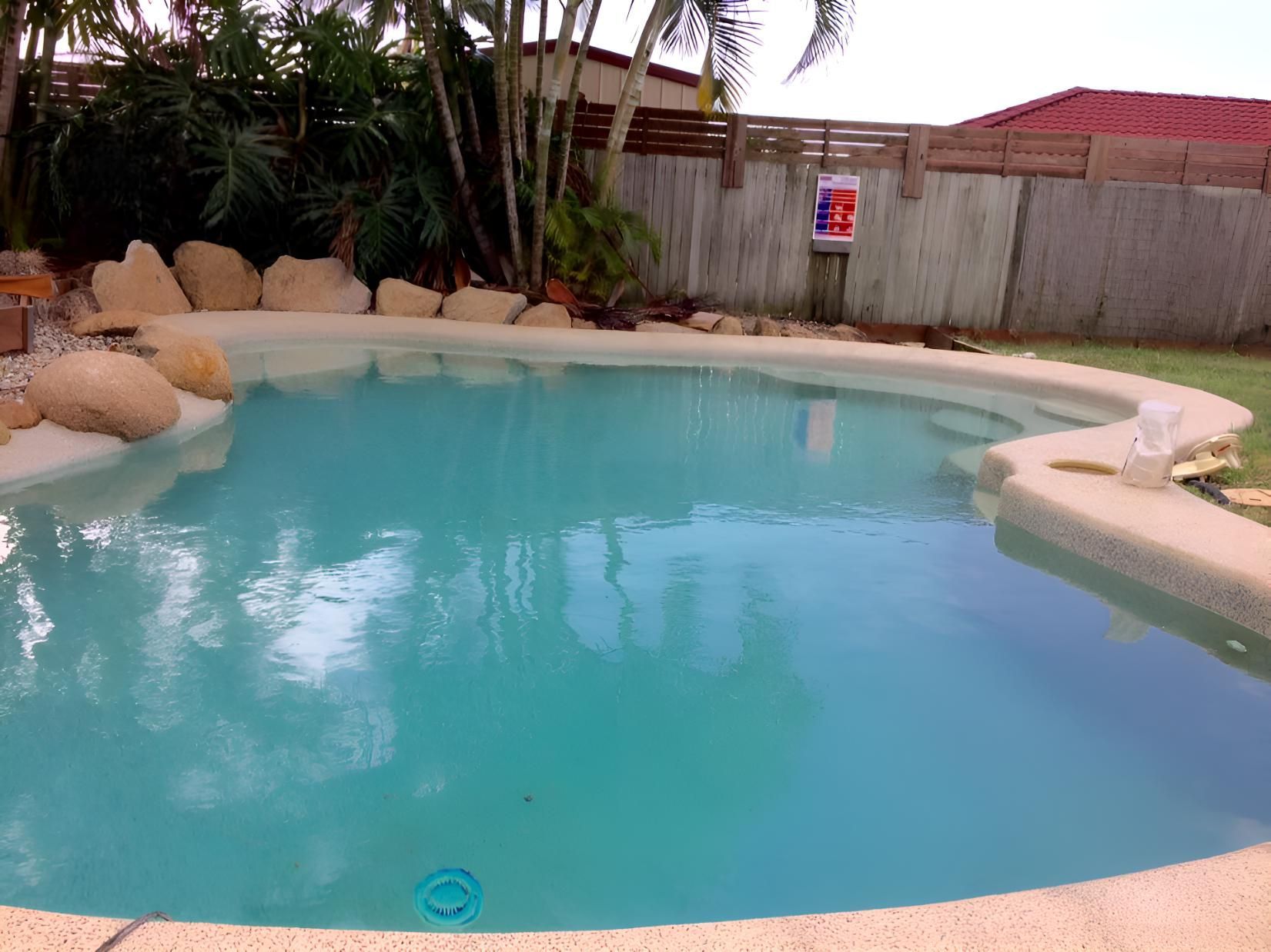 A Large Swimming Pool With A Fence In The Background — Aqua Duck Pool Care In Buderim, QLD