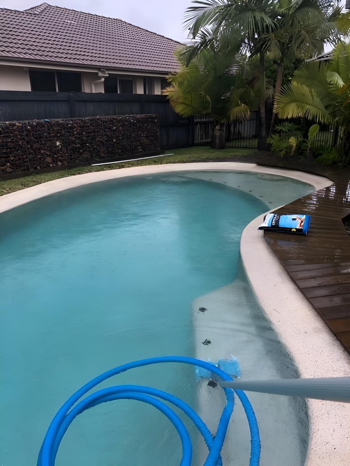 A Large Swimming Pool With A Blue Hose Attached To It — Aqua Duck Pool Care In Maroochydore, QLD