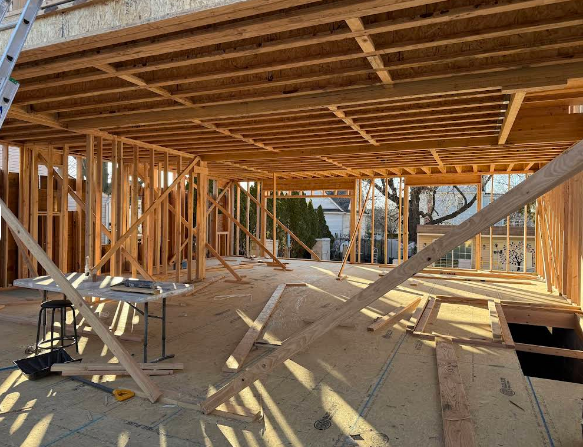 Interior of a building under construction, wooden frames, ceiling beams, natural light.