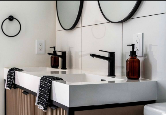 Modern bathroom with double sinks, black fixtures, and amber soap dispensers.