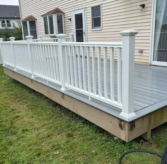White deck railing on a wooden deck with green grass background.
