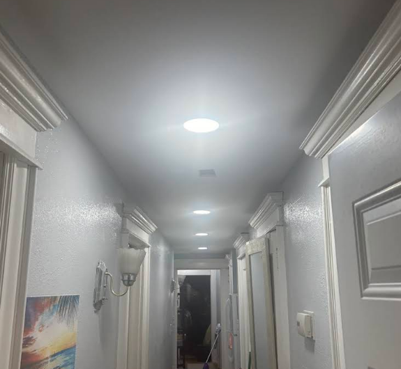 A hallway with recessed ceiling lights and white trim. A painting hangs on the left wall.