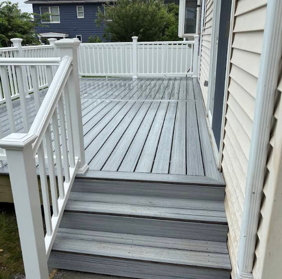 Gray deck with white railing and stairs leading to a door.