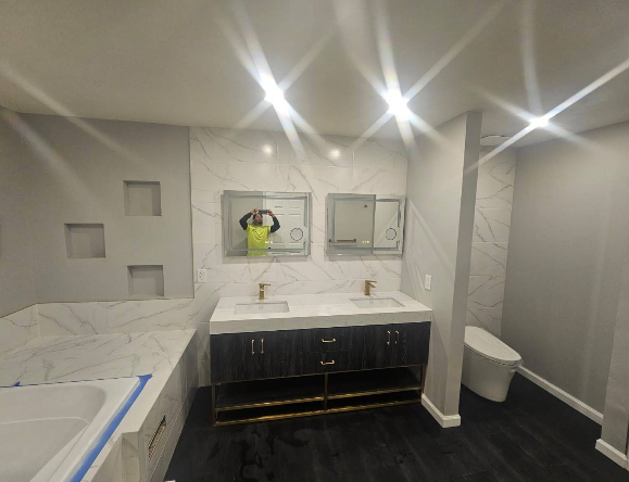 Modern bathroom with marble tile, dark vanity, and a toilet.