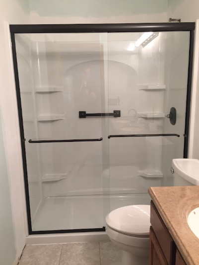 Glass shower stall with beige tile walls and a white shower base in a bathroom
