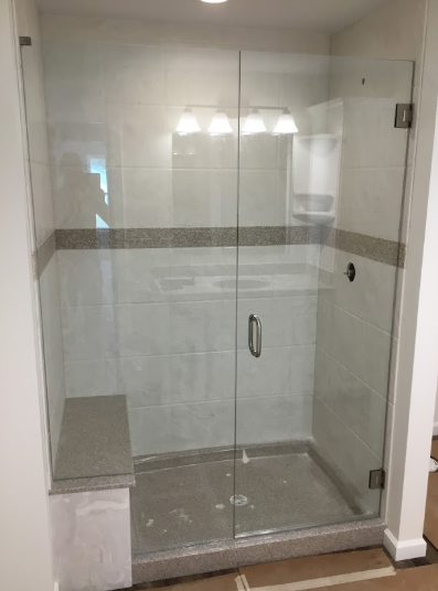 Glass shower enclosure with chrome handle in a tiled bathroom alcove