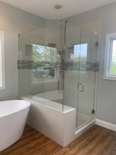 Modern bathroom with glass walk-in shower, freestanding tub, and wood-look floor tiles