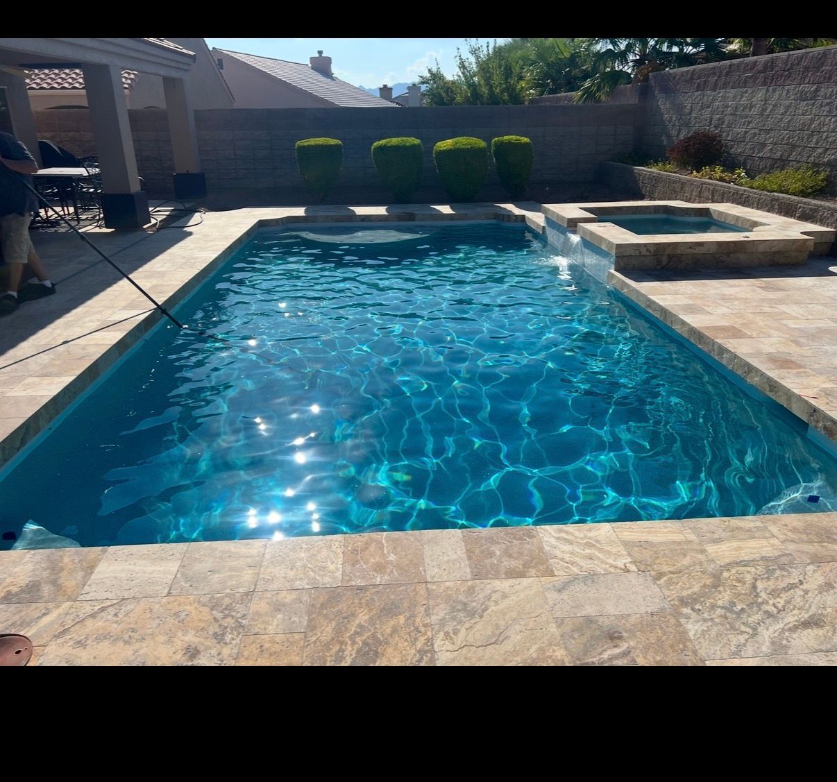 A rectangular swimming pool with turquoise water and a small spa. The surrounding patio is tan.