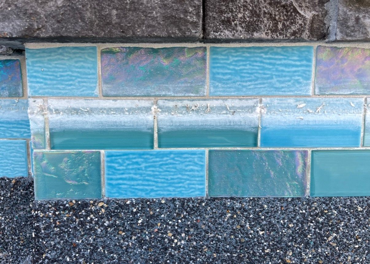 Blue and iridescent tile border on a dark textured surface.