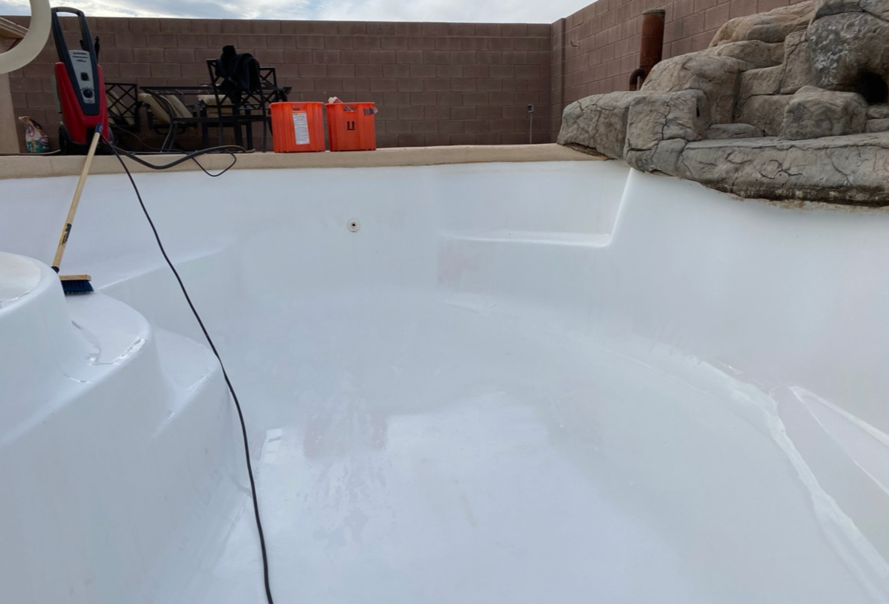 Newly painted white swimming pool with steps, against a neutral-toned fence.