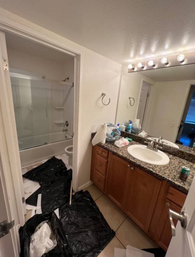 A bathroom messy full of trash bags and towels on the floor.