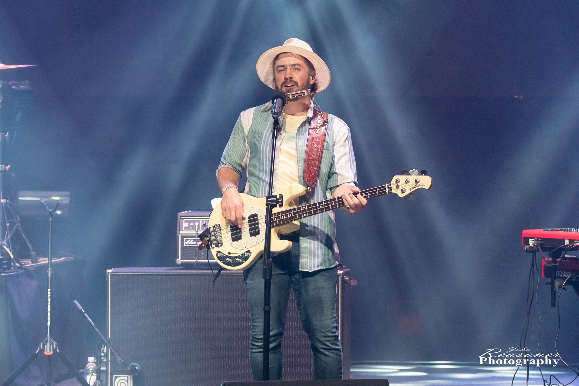 A man is playing a guitar and singing into a microphone on a stage.