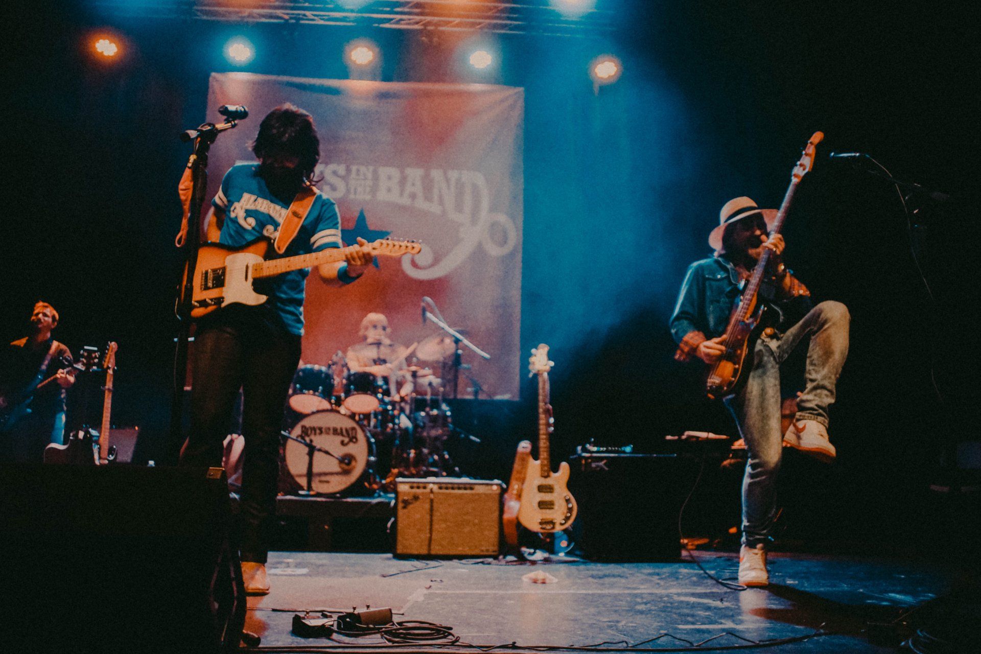 A man playing a guitar in front of a banner that says