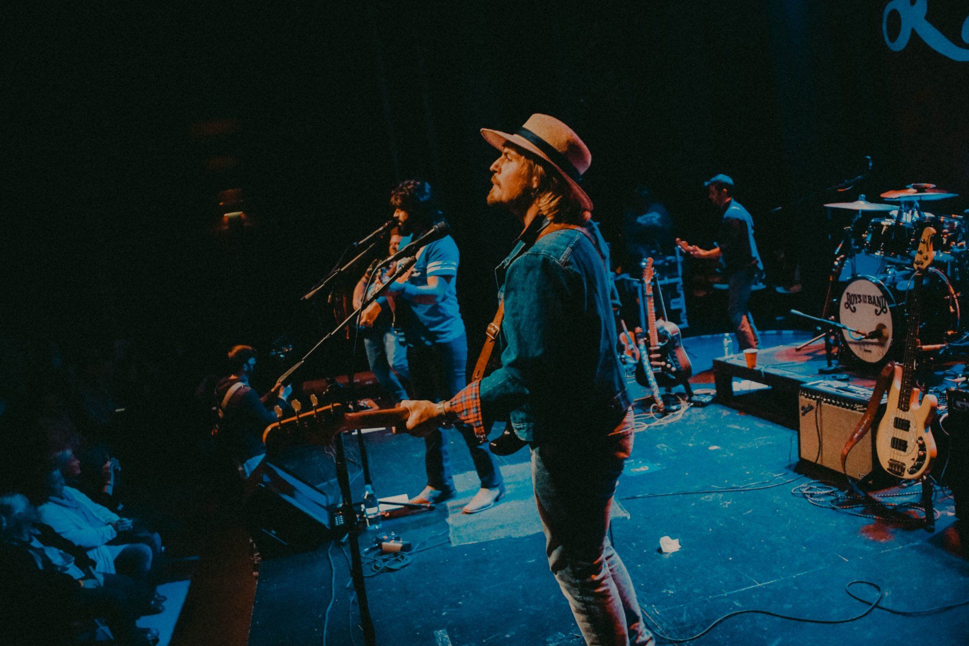 A man in a hat is playing a guitar on stage
