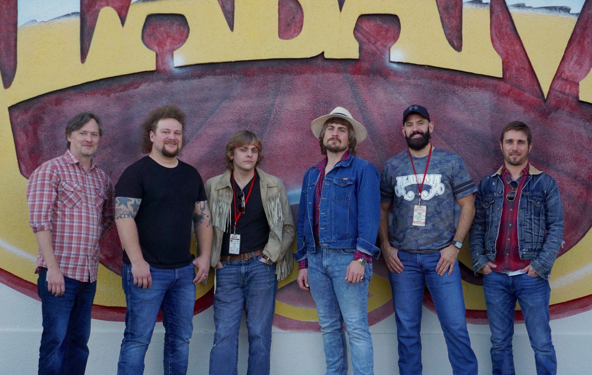 A group of men are posing for a picture in front of a mural.