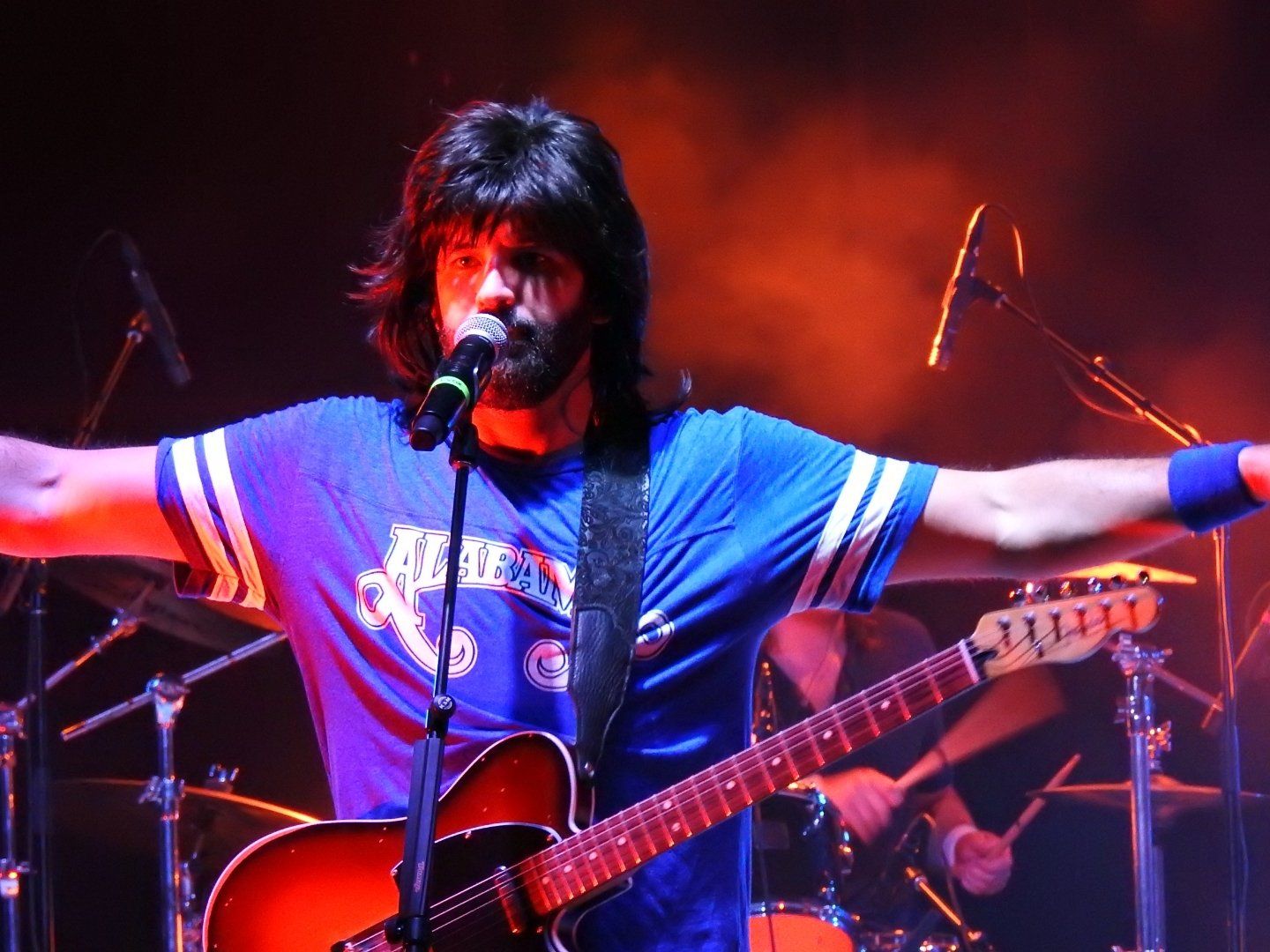 A man singing into a microphone while playing a guitar