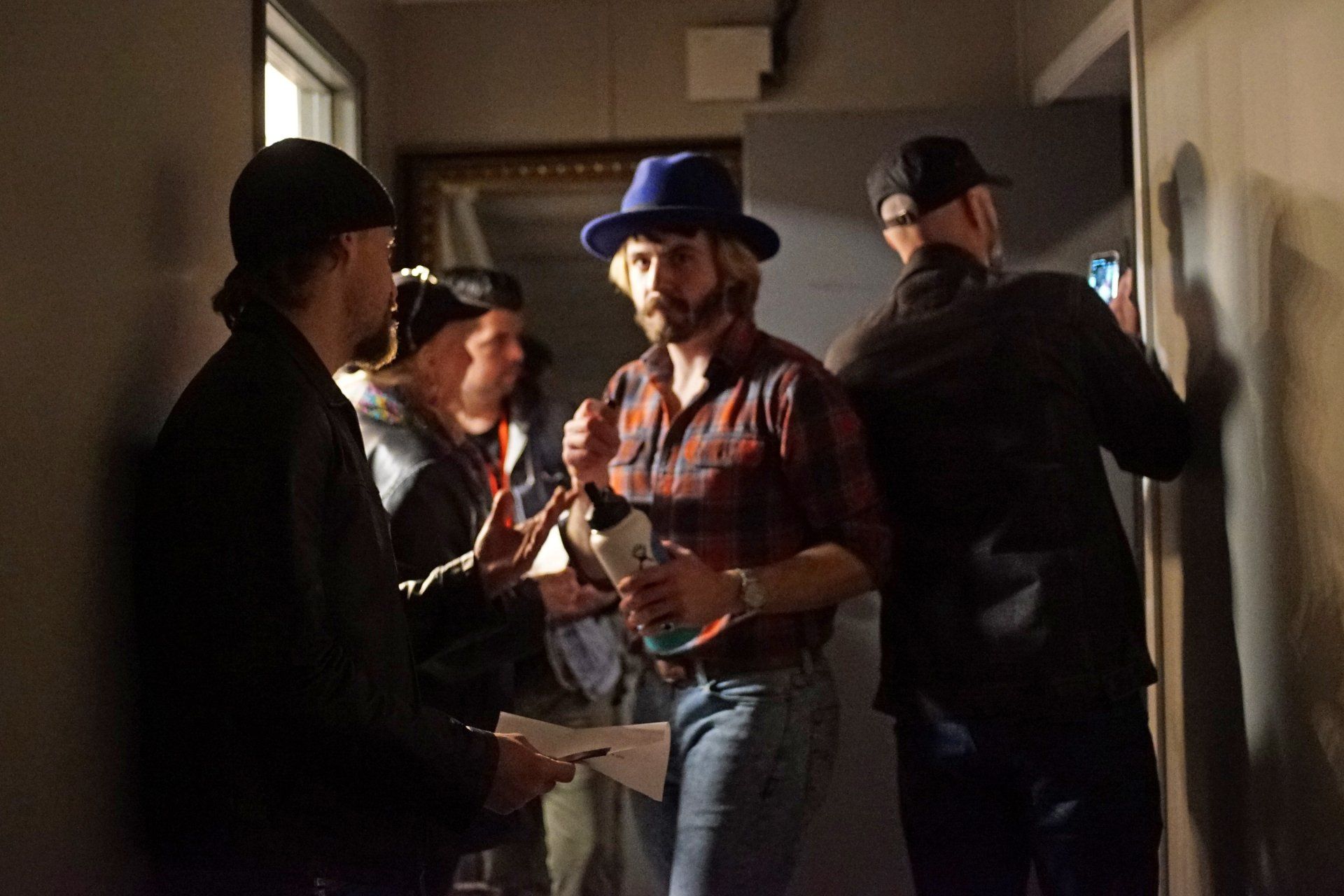 A group of men are standing in a hallway talking to each other.