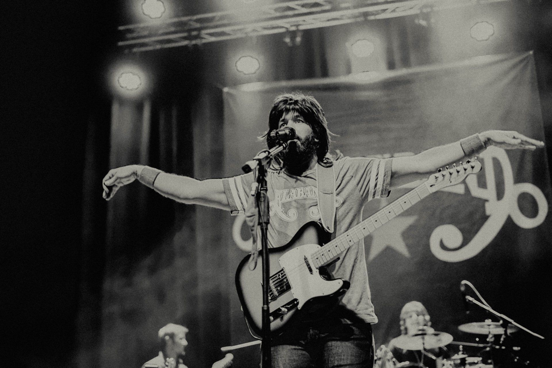 A man singing into a microphone while playing a guitar