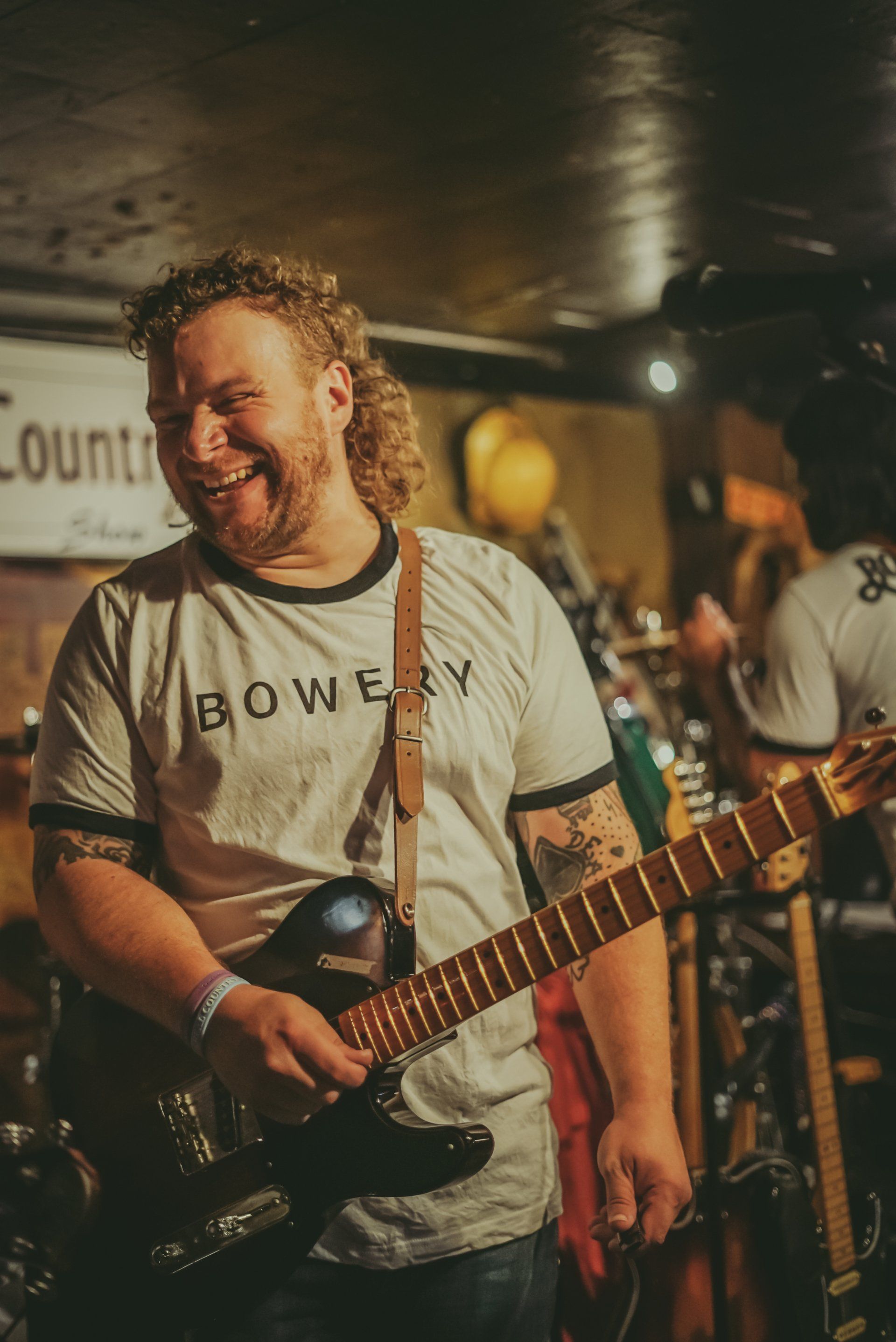 A man is playing a guitar on stage and smiling.