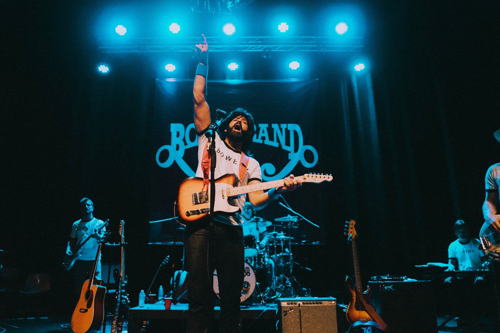 A man singing into a microphone while playing a guitar on stage