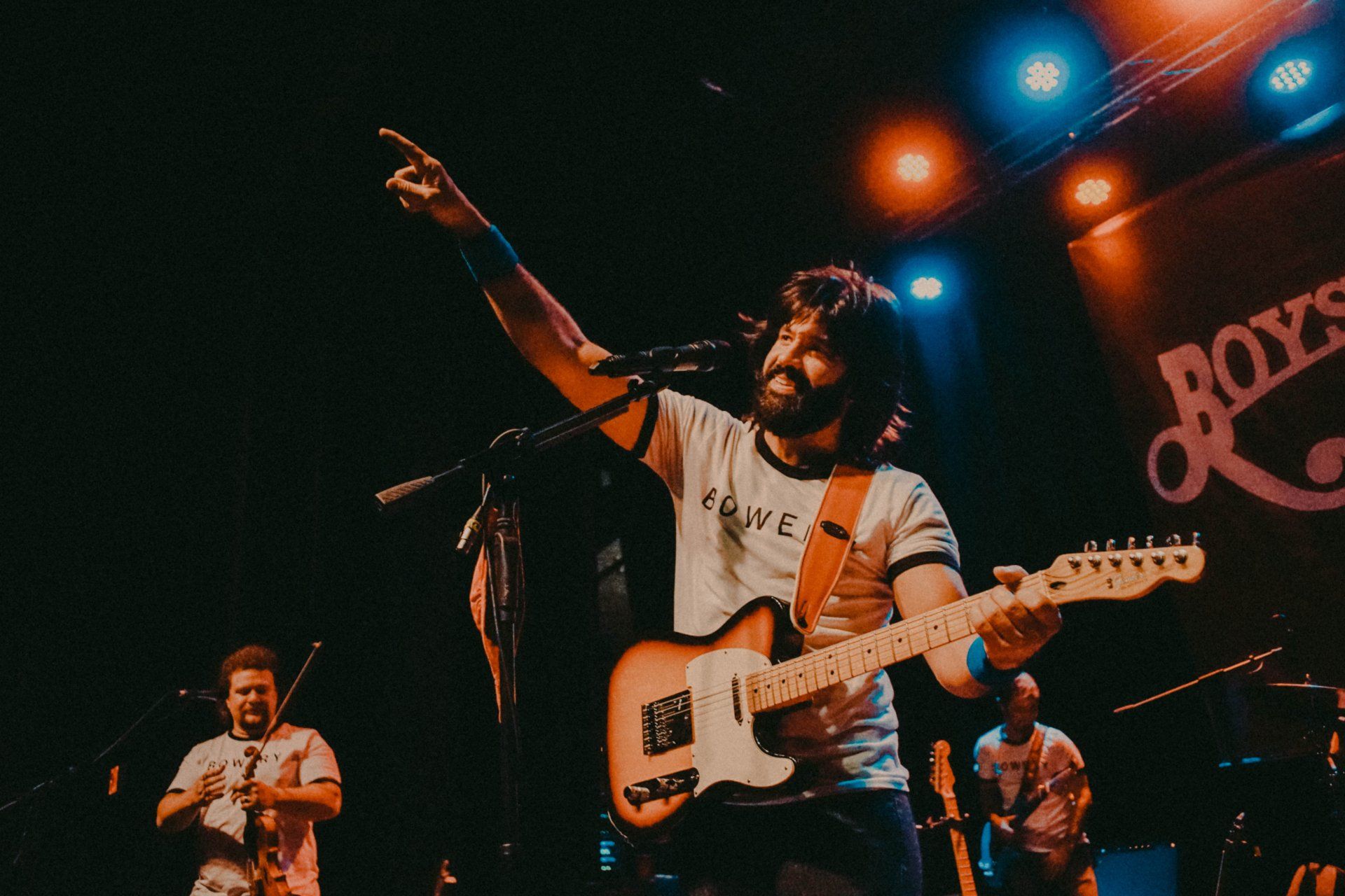 A man is playing a guitar and singing into a microphone on a stage.