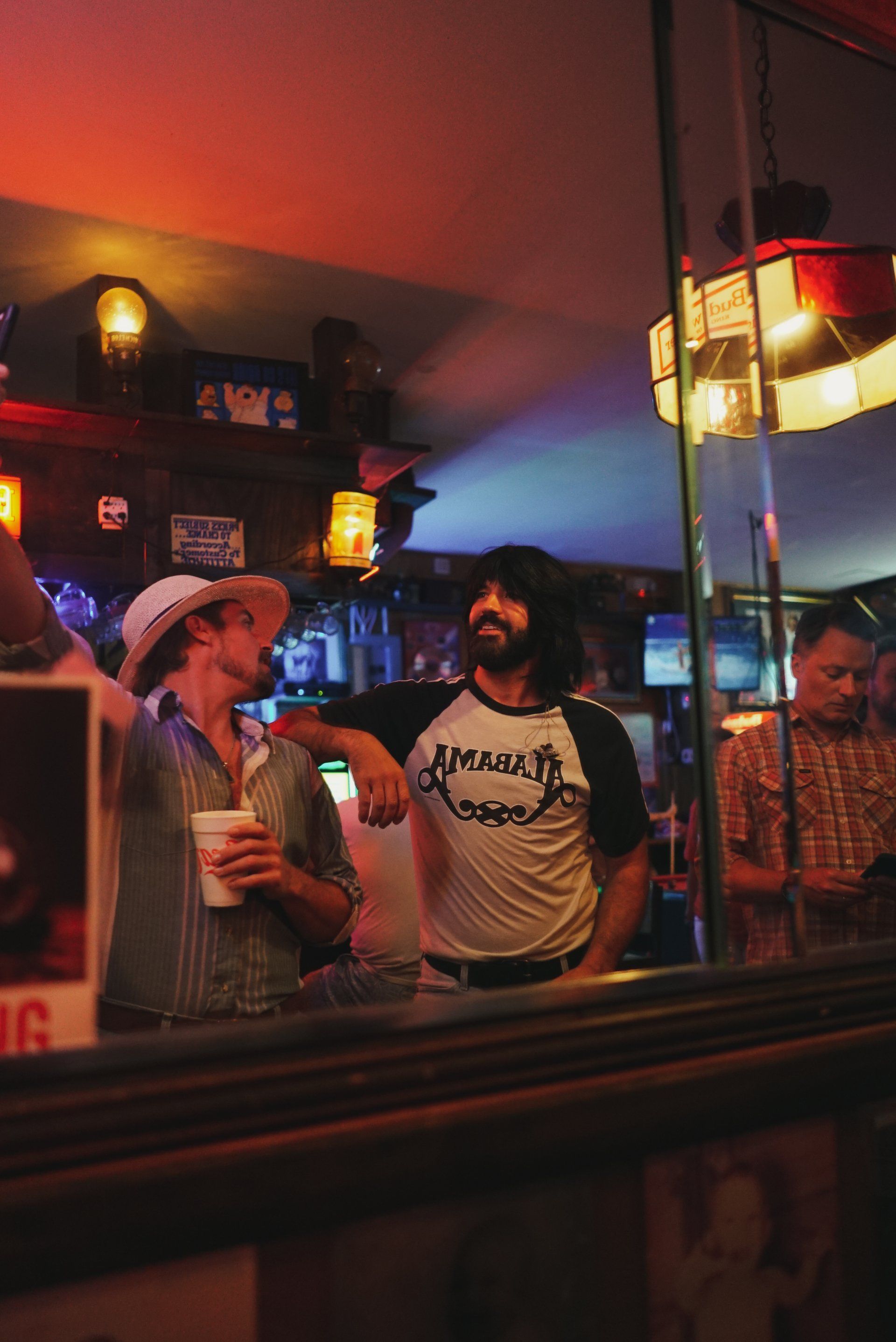 A group of men are standing in a bar talking to each other.