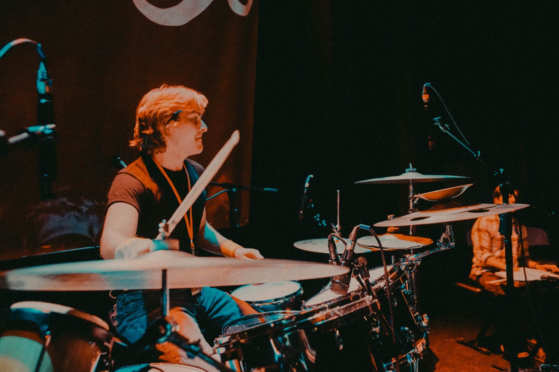 A man is playing drums in a band on a stage