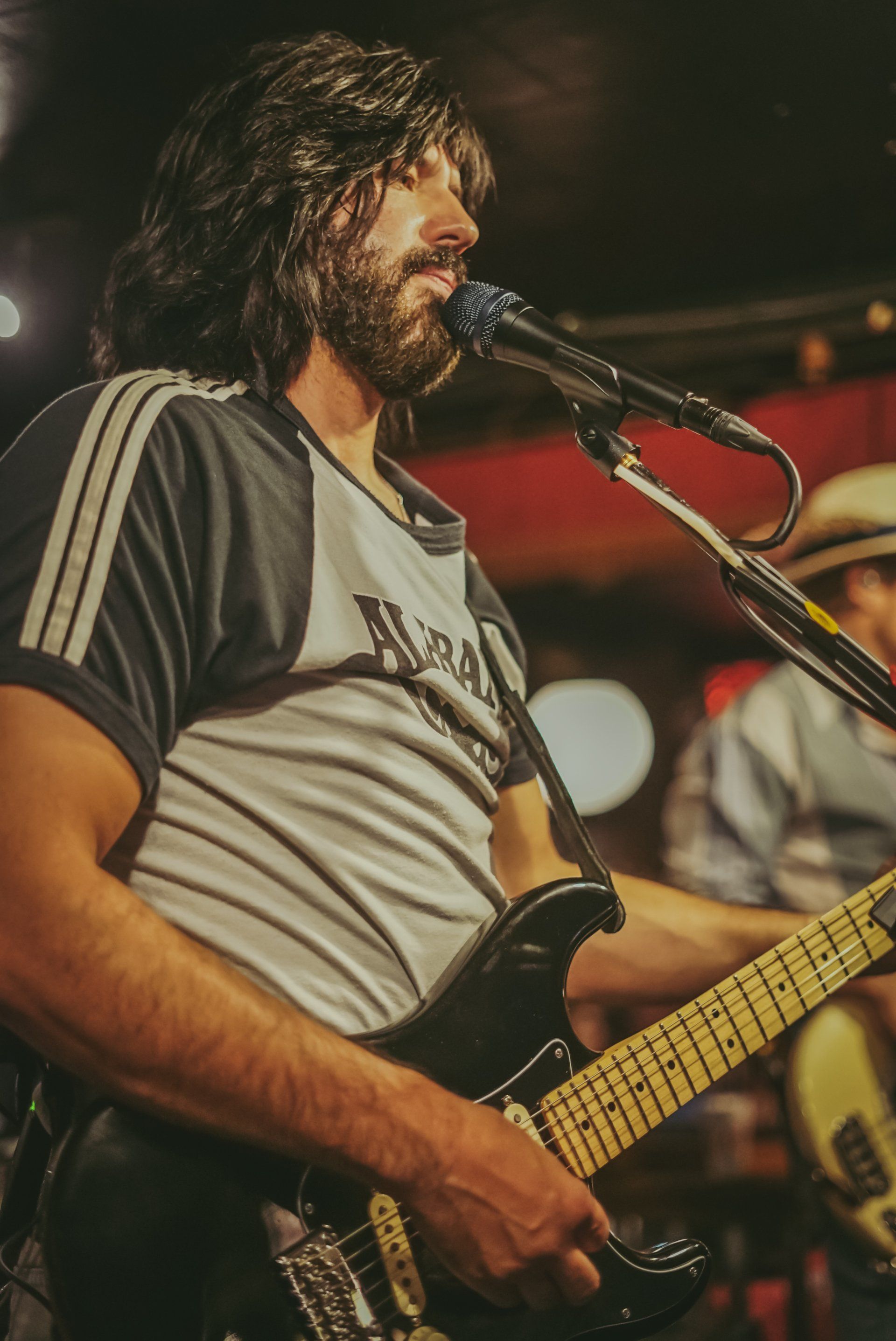 A man with a beard is playing a guitar and singing into a microphone.