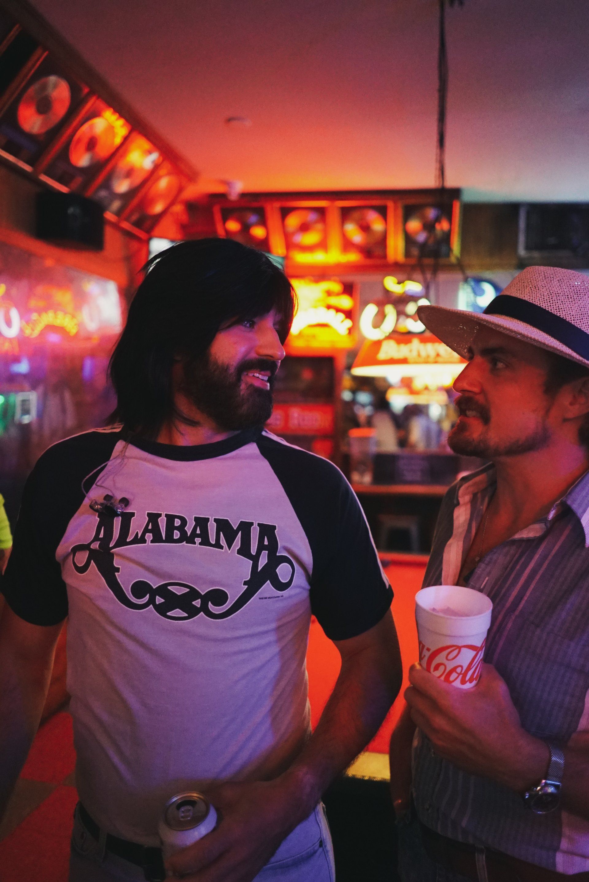 A man wearing an alabama shirt is standing next to another man