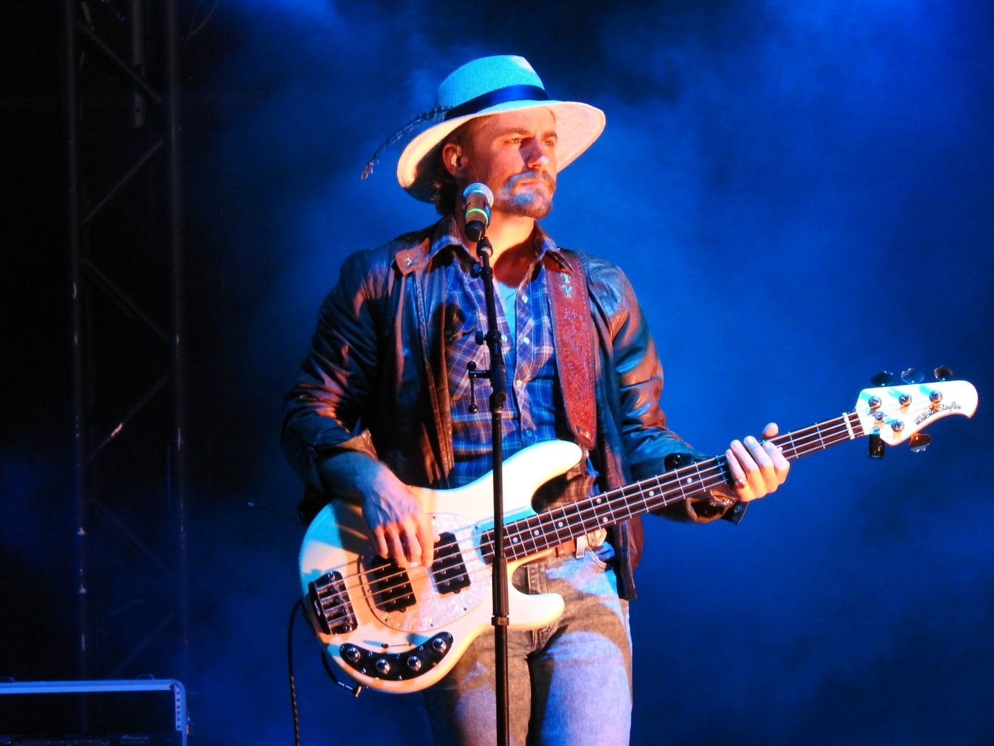 A man in a hat is playing a guitar and singing into a microphone