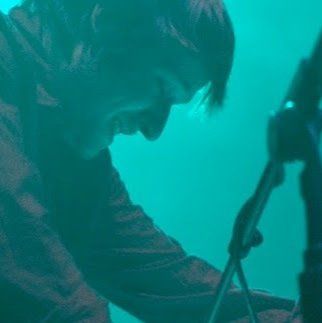 A man is sitting in front of a microphone in a dark room.
