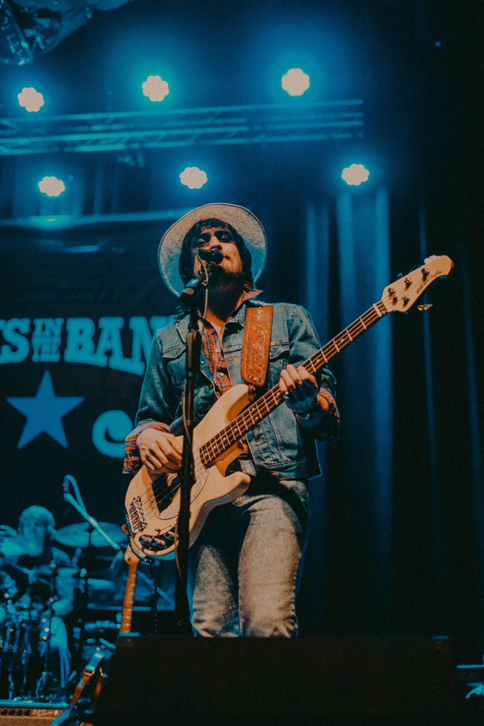 A man in a cowboy hat is playing a guitar on stage