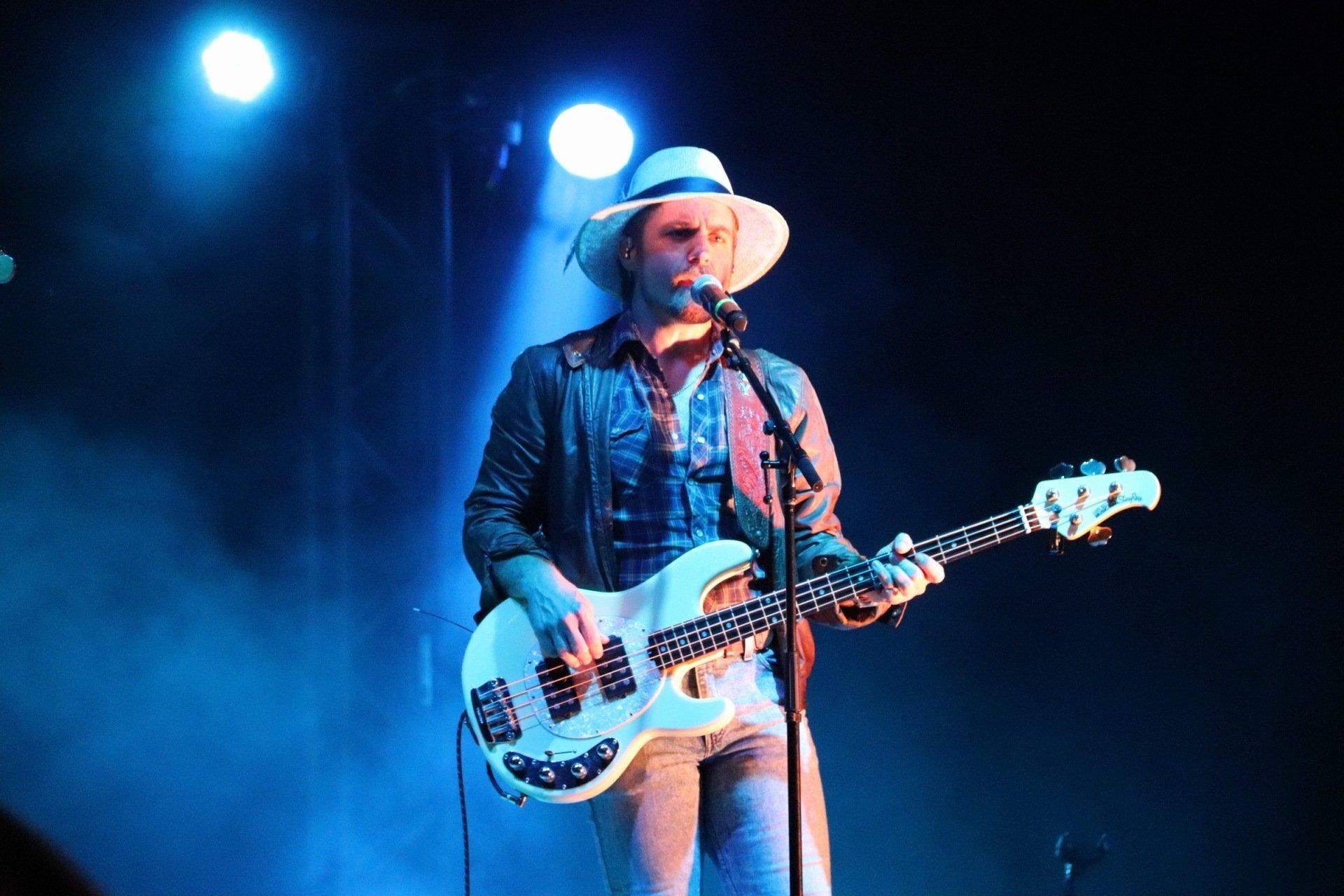 A man in a hat is playing a guitar and singing into a microphone