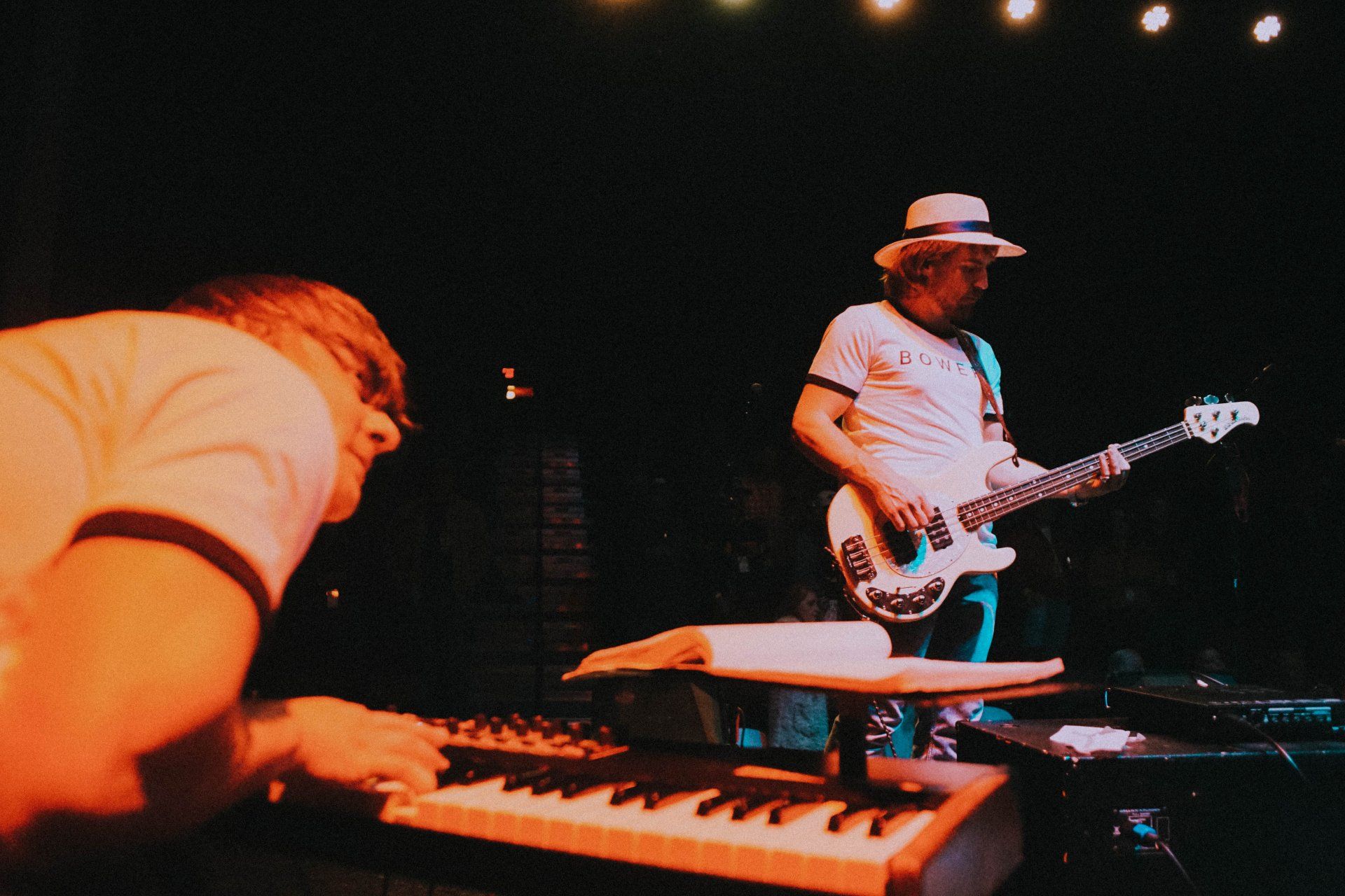 A man playing a keyboard while another man plays a guitar