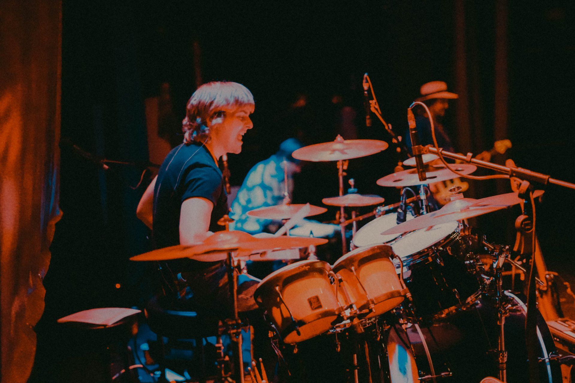 A man is playing drums in a dark room