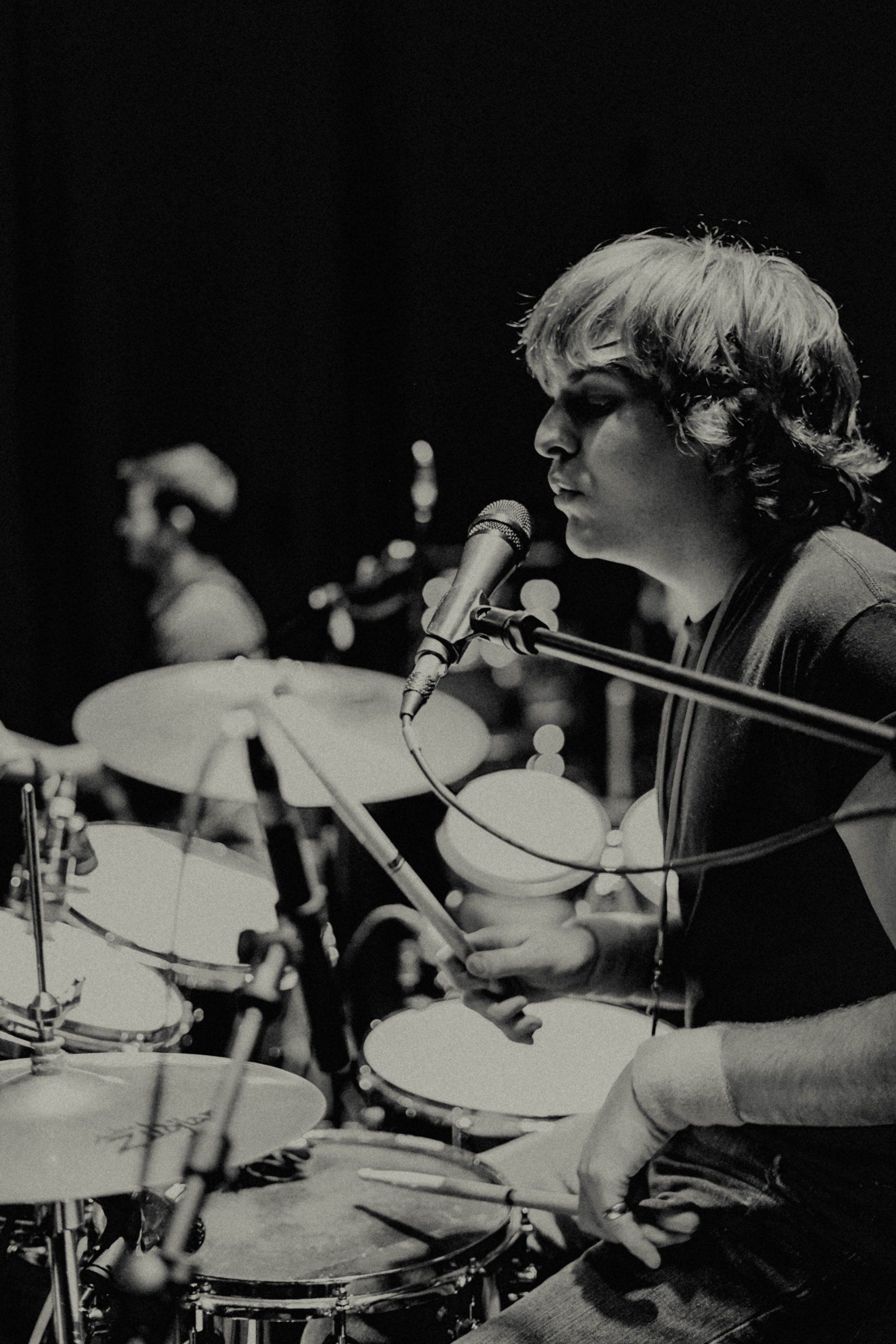 A man is playing drums and singing into a microphone