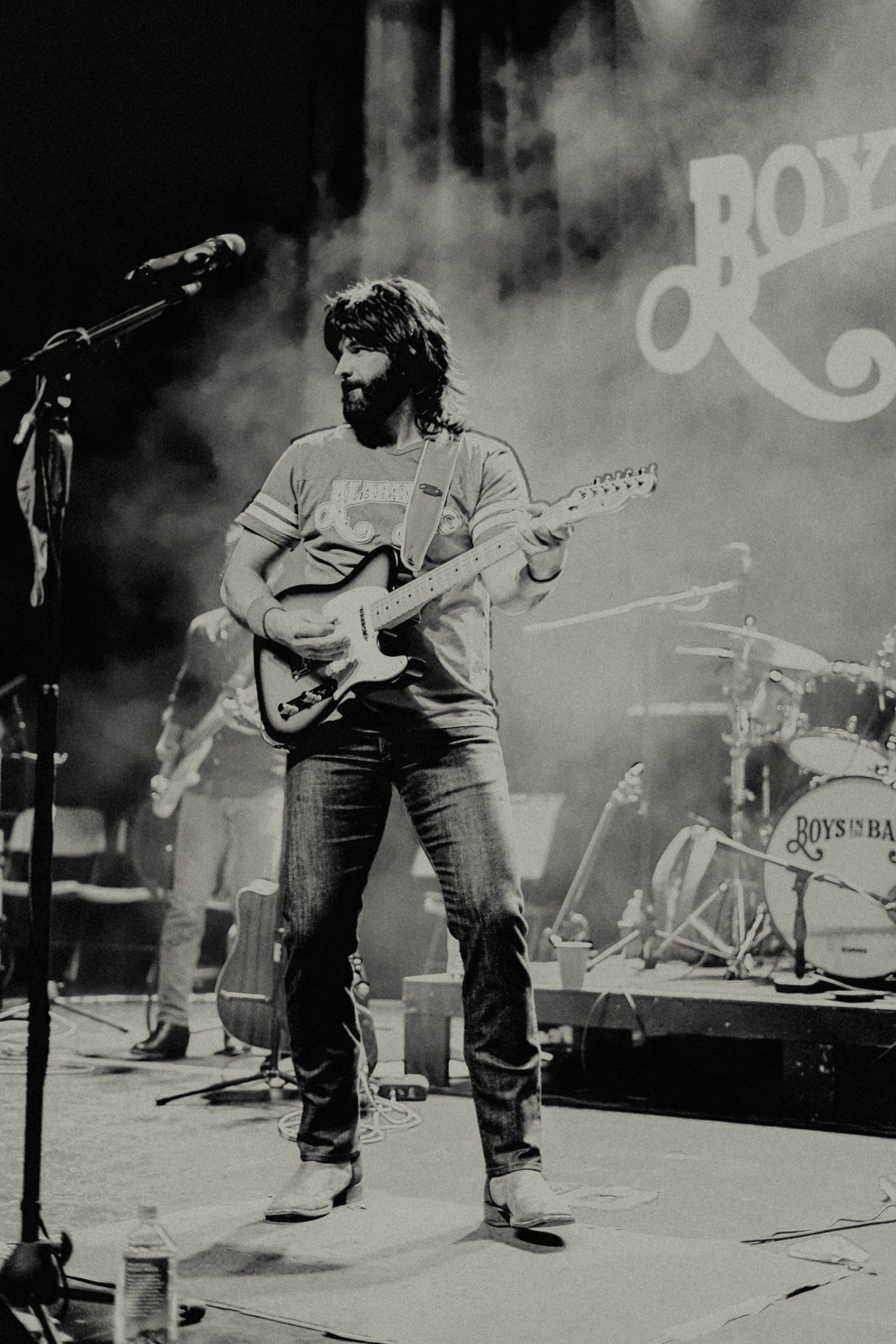 A black and white photo of a man playing a guitar on stage