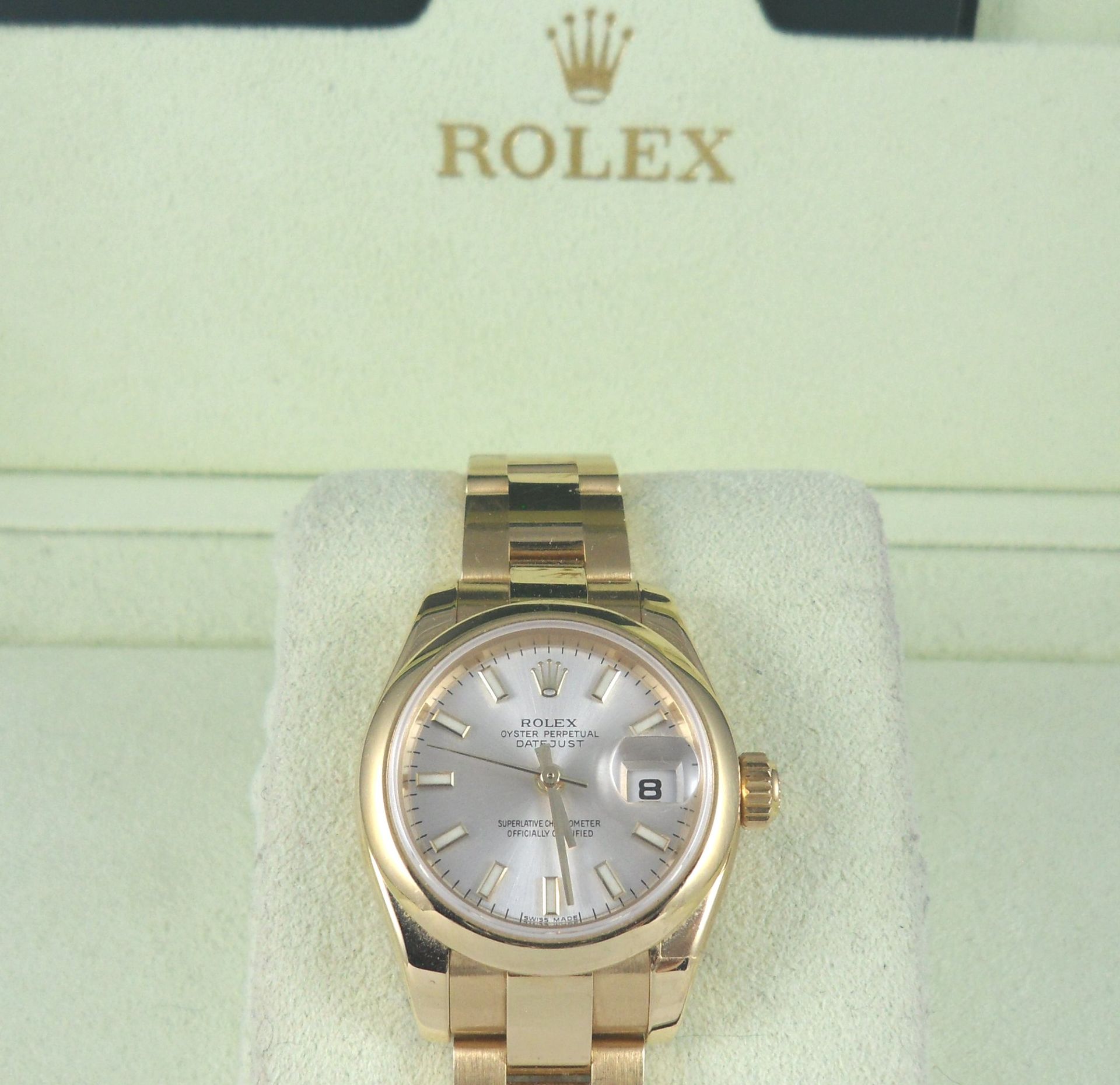 A gold rolex watch sits in front of a box