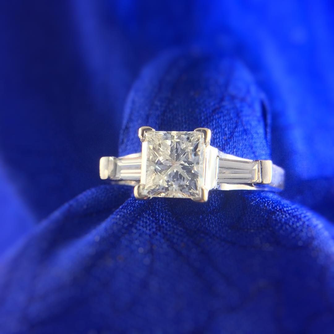 A diamond ring is sitting on a blue cloth.