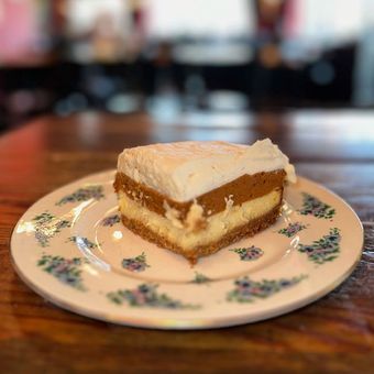 a slice of cheesecake is on a white plate on a wooden table