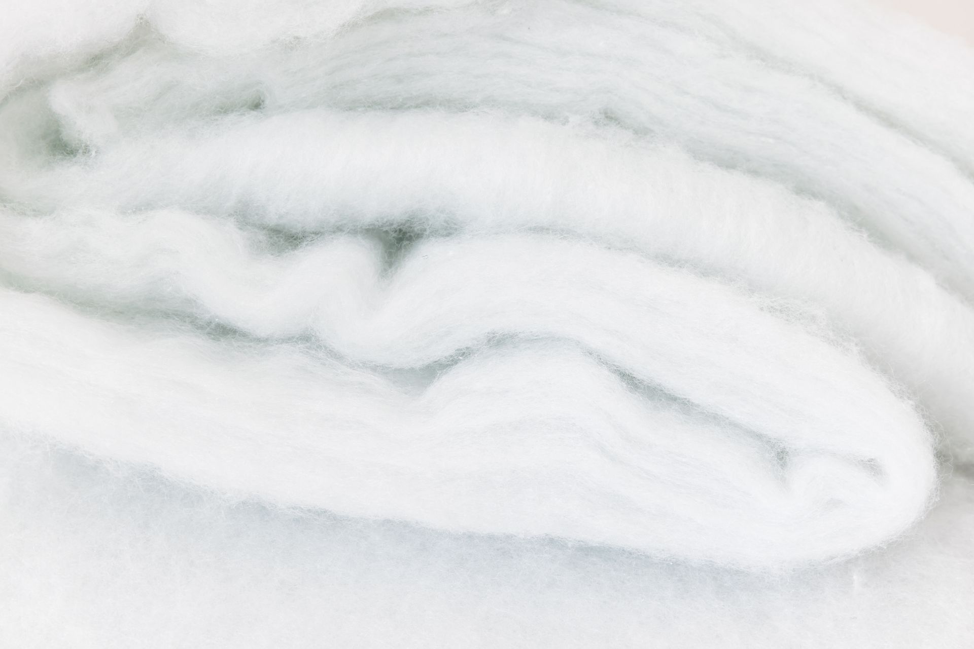 Stacked white rolled towels on a soft white surface